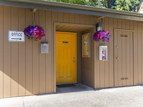 Woodburn apartment for rent - the front of a building with a yellow door and two hanging flowers