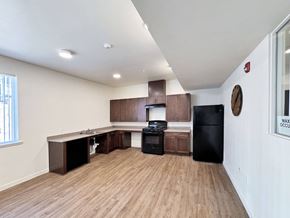 Paradise apartment for rent - a kitchen and living room with wood flooring and a black refrigerator