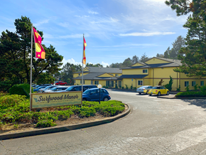 Lincoln City apartment for rent - Surfwood Manor sign in front of a building with flags.