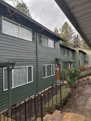 Portland apartment for rent - A green house with a black fence and a brown staircase.