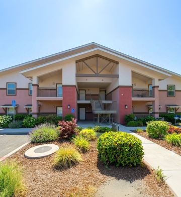 Diamond Springs apartment for rent - A building with a red and beige facade has a circular planter in front.