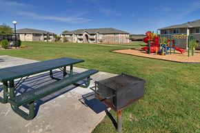 Red Bluff apartment for rent - a picnic table and a grill in a park with a playground