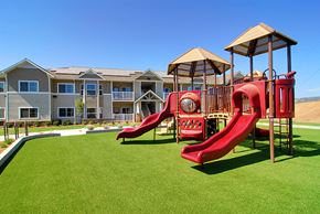 Oroville apartment for rent - a playground with a red playset in front of an apartment building