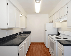 Tigard apartment for rent - A kitchen with white cabinets and black countertops.