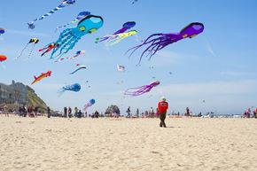 Lincoln City apartment for rent - A beach scene with a person in the foreground and many kites flying in the sky.