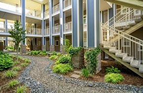 Oroville apartment for rent - A gravel path leads to a building with a staircase.