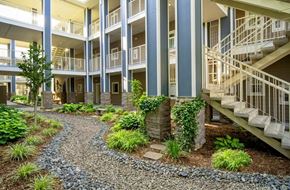 Oroville apartment for rent - A gravel path leads to a building with a staircase.