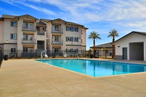 Chico apartment for rent - A swimming pool in front of a building with a fence and palm trees.