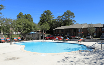 Hoover apartment for rent - A swimming pool surrounded by trees and a building in the background.