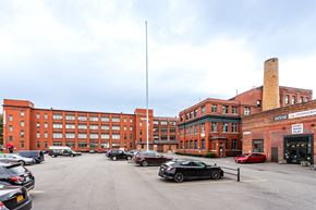 Rochester apartment for rent - a parking lot in front of a large brick building with cars parked