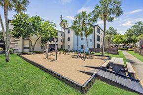 St Petersburg apartment for rent - A playground with a slide and a picnic table is surrounded by palm trees.