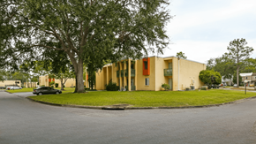 Panama City apartment for rent - A yellow building with a red door is surrounded by trees.