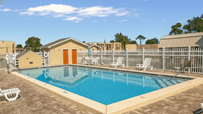 Panama City apartment for rent - A pool with a brown building and white chairs.