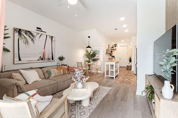 Lakeland apartment for rent - A living room with a couch, a coffee table, and a painting of a palm tree on the wall.
