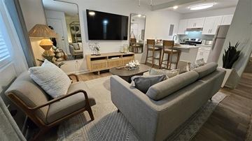 Tampa apartment for rent - A living room with a grey couch and a wooden chair.