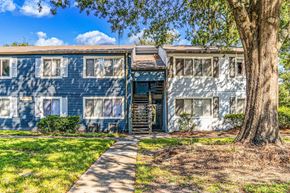 Jacksonville apartment for rent - A tree stands in front of a blue and white building.