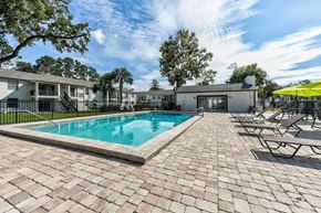 Jacksonville apartment for rent - A swimming pool surrounded by a brick patio and lounge chairs.