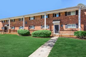 Athens apartment for rent - A brick building with a white roof and a green lawn in front.