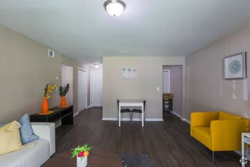 Decatur apartment for rent - A living room with a white couch, a yellow chair, and a coffee table with a vase of flowers on it.