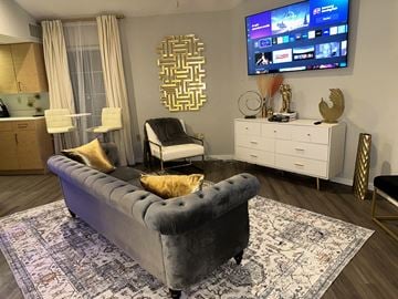 St. Louis apartment for rent - A modern living room with a grey sofa and a flat screen TV mounted on the wall.