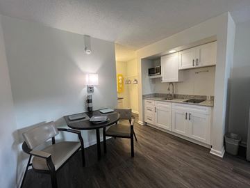 Marietta apartment for rent - A kitchen with a table and chairs in the foreground and a countertop with a microwave and oven in the background.