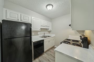 Hoover apartment for rent - A black refrigerator sits in a kitchen with white cabinets and a white countertop.