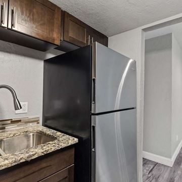 Tallahassee apartment for rent - A black refrigerator in a kitchen with a granite countertop.