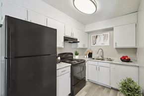 Dublin townhouse for rent - a kitchen with white cabinets and black appliances and a black refrigerator