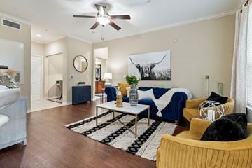 Katy apartment for rent - A living room with a blue couch and a painting of a bull on the wall.