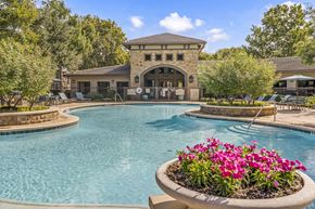 San Antonio apartment for rent - A pool with a building in the background and a flower pot in the foreground.