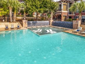 San Antonio apartment for rent - A swimming pool surrounded by palm trees and lounge chairs.
