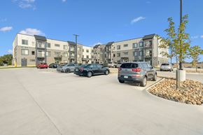 Hiawatha apartment for rent - A parking lot with cars and apartment buildings in the background.