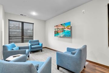 Coralville apartment for rent - A living room with blue chairs and a painting of a pool.