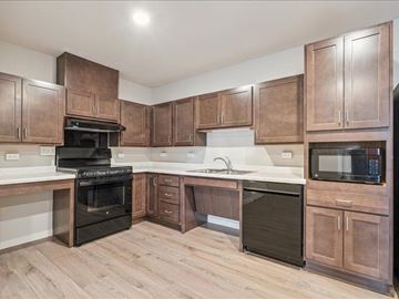 Iowa City apartment for rent - A kitchen with brown cabinets and black appliances.