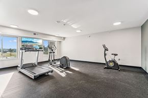 Hiawatha apartment for rent - A spacious gym with a treadmill, exercise bike, and weights.