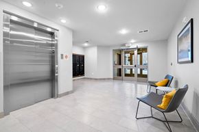 Coralville apartment for rent - A spacious hallway with a chair and a painting on the wall.