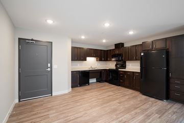 Plymouth apartment for rent - a kitchen with black appliances and wooden flooring and dark cabinets