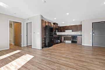Shakopee apartment for rent - a kitchen and living room with wood flooring and a black refrigerator