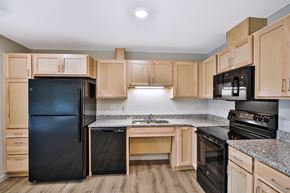 Kasson apartment for rent - A kitchen with black appliances and wooden cabinets.