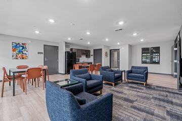 Crystal apartment for rent - A modern living room with blue chairs and a wooden table.