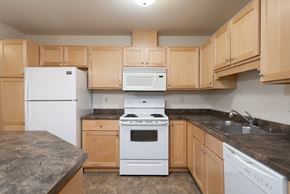 White Bear Lake apartment for rent - A kitchen with a white refrigerator, white oven, and wooden cabinets.