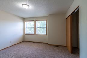 Albany townhouse for rent - A room with a carpeted floor, a window with trees visible outside, and a closed door on the right.