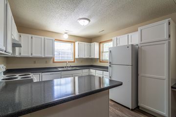 Albany townhouse for rent - A kitchen with white cabinets and a black counter top.