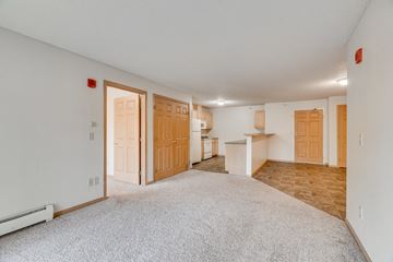 Bloomington apartment for rent - the living room and kitchen of an apartment with white carpet and wood doors