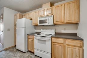 Bloomington apartment for rent - A kitchen with wooden cabinets and white appliances.