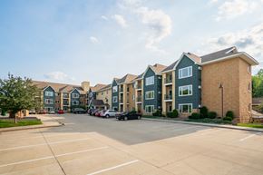Maple Grove apartment for rent - A parking lot in front of a row of apartment buildings.