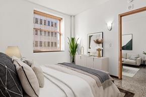 St Paul apartment for rent - A bedroom with a bed, a mirror, and a window with blinds.