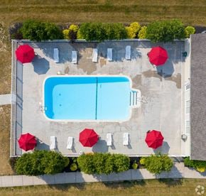 Rochester apartment for rent - An aerial view of a pool surrounded by red umbrellas and trees.