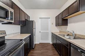 Rochester apartment for rent - A kitchen with dark brown cabinets and a black refrigerator.