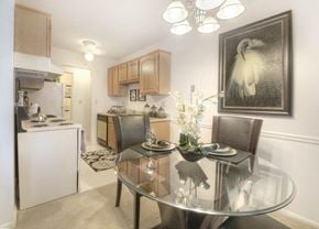 Rochester apartment for rent - Dining space with modern glass table and kitchen view at Chili Heights Apartments, Rochester, NY